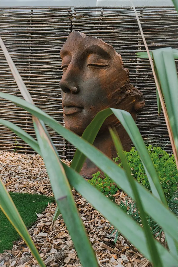 amenagement d'un jardinn par tchanque service avec une statue de visage au millieux